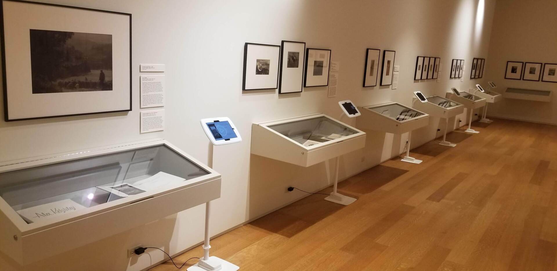 An art gallery displays photographs, with informational kiosks on display.