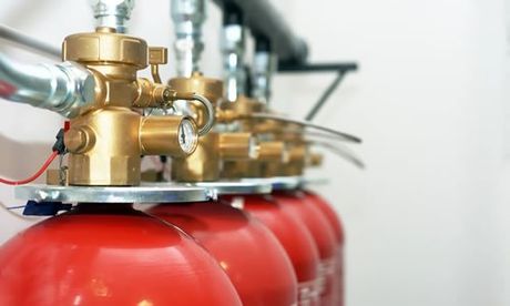 Cilindros rojos de extinción de incendios con válvulas de latón y tuberías de plata.