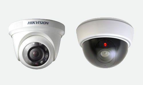 Dos cámaras de seguridad tipo domo blancas sobre fondo gris. La de la izquierda tiene el logotipo de