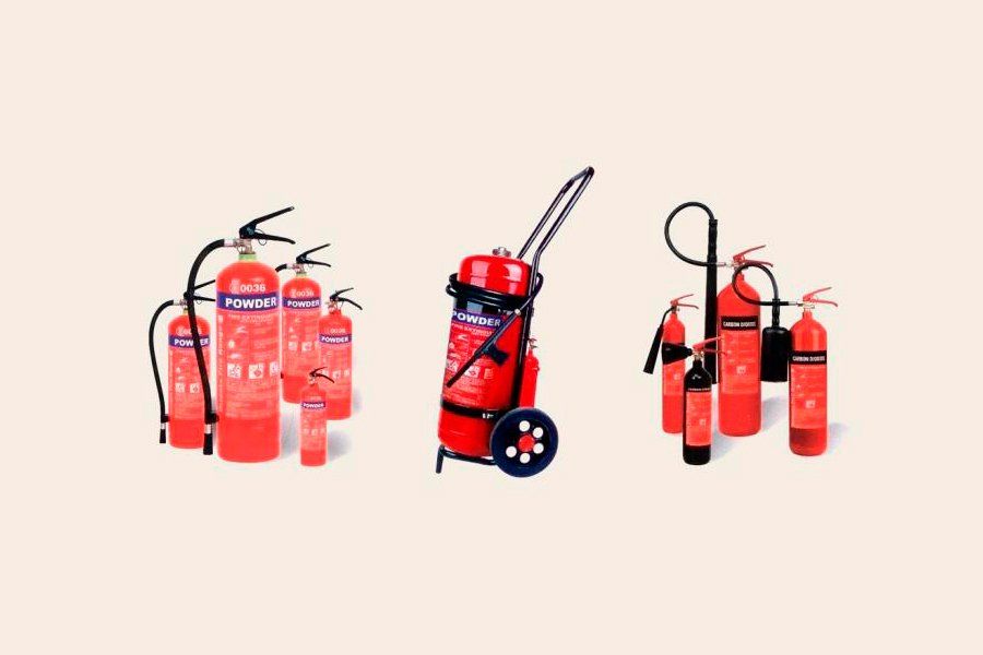 Extintores de diferentes tamaños, de color rojo, dispuestos en soportes y en un carro.