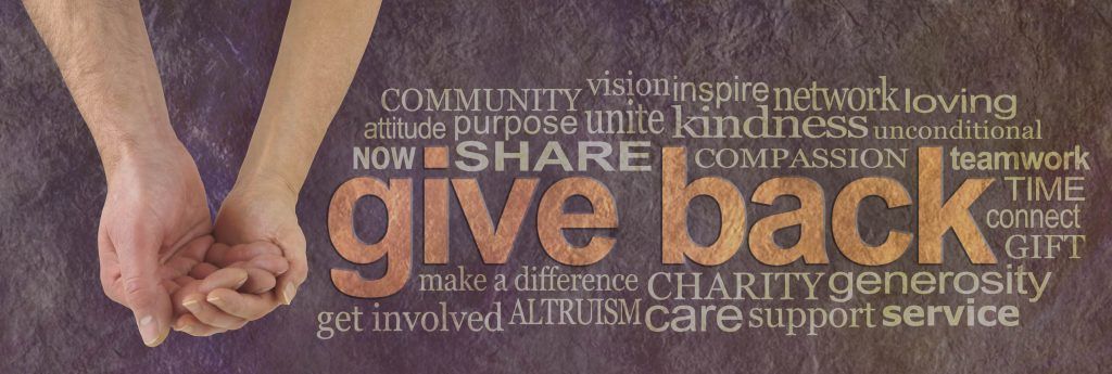 Campaign banner with female hand holding male cupped hand on left and a GIVE BACK word cloud on right against a rustic parchment background
