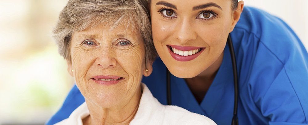 personale di servizio e una donna anziana sorridono in posa per una foto