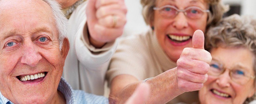 persone anziane in posa per una foto con il pollice alzato