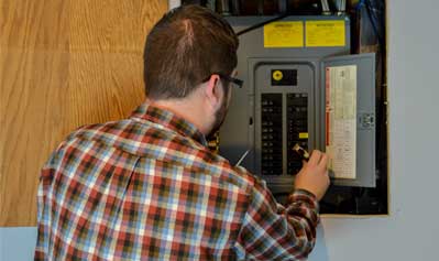 Man fixing fuse box —Electric Panel Installation in York, PA Man fixing fuse box —Electric Panel Installation in York, PA