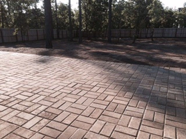 A brick driveway with trees in the background