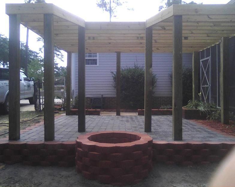 A wooden pergola with a fire pit in the middle