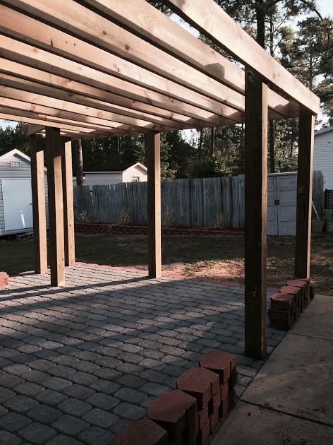 A wooden pergola with bricks underneath it