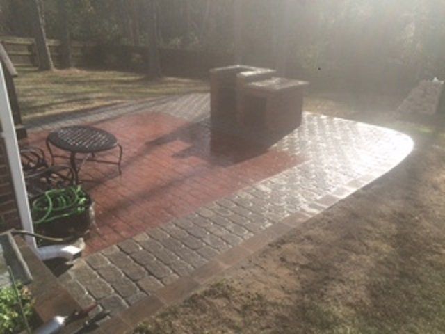 A brick walkway leading to a patio with a table and chairs