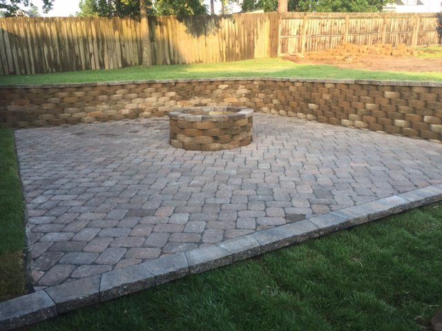 A brick patio with a fire pit in the middle of it