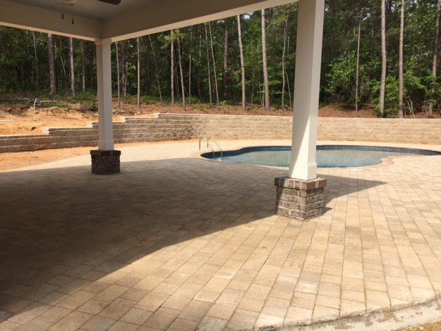 A patio with a pool and trees in the background.
