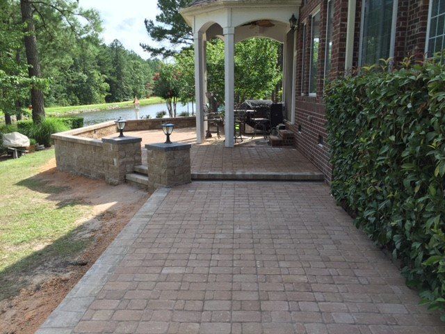 A brick walkway leading to a porch with a gazebo.