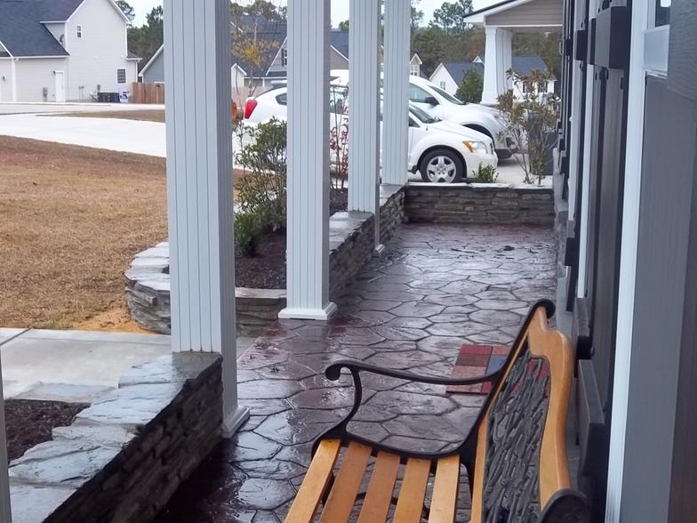 A porch with a bench and a car parked in the background