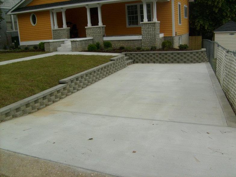 A yellow house with a concrete driveway in front of it
