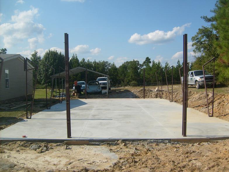 A concrete driveway with a carport and a house in the background
