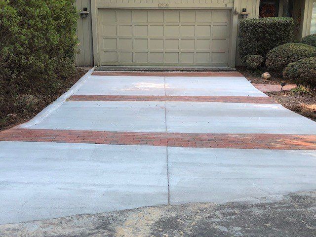 A concrete driveway with a brick border is leading to a garage door.