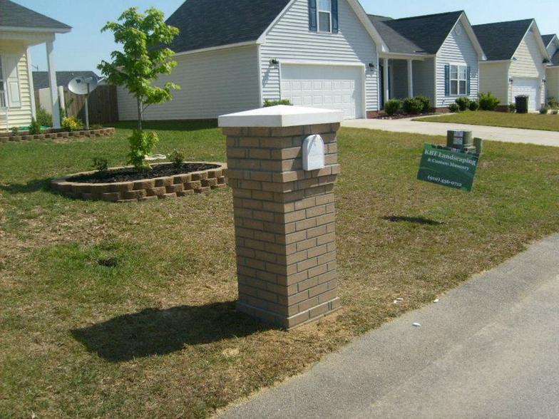 A brick post in front of a row of houses