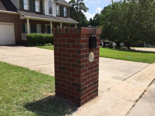 A brick post with a mailbox in front of a house