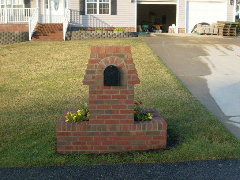 A brick mailbox in the shape of a dog house
