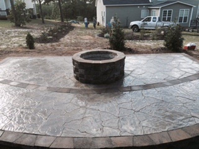 A fire pit is sitting on a patio in front of a house.