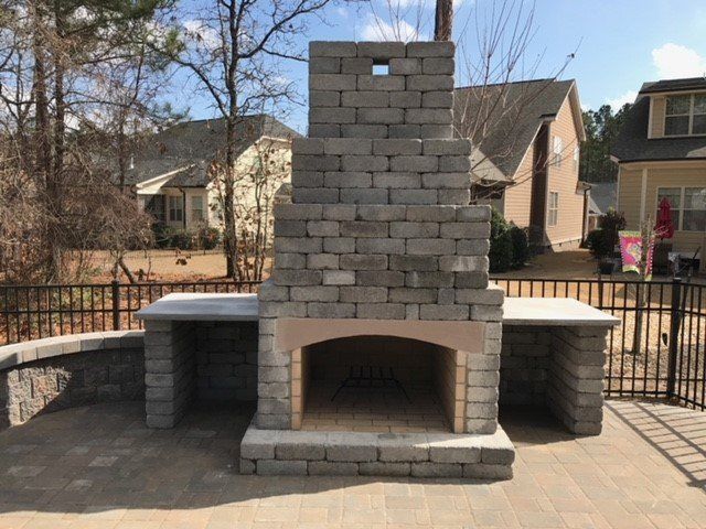 A brick fireplace on a patio in front of a house