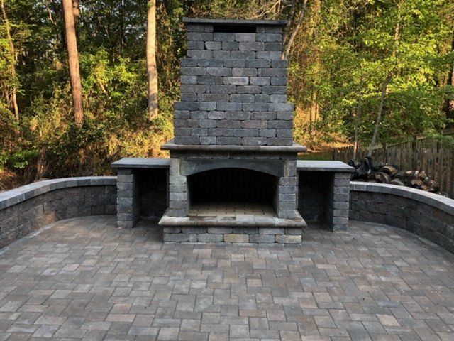 A brick fireplace on a patio with trees in the background