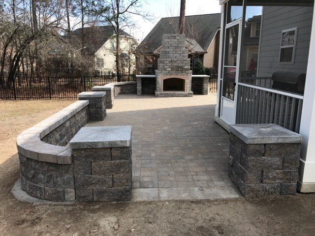 A patio with a fireplace and a screened in porch.