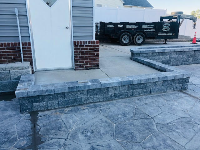 A black dump truck is parked in front of a brick house.