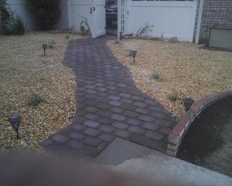 A brick walkway leading to a white garage door