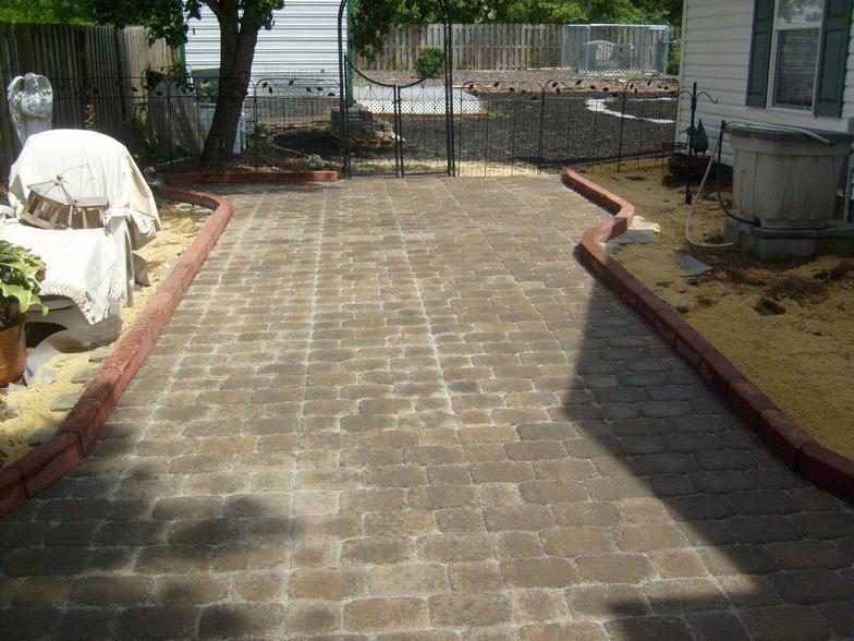 A backyard with a brick walkway leading to a house