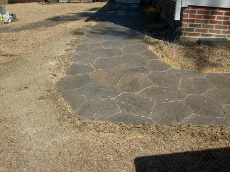 A stone walkway in front of a brick house