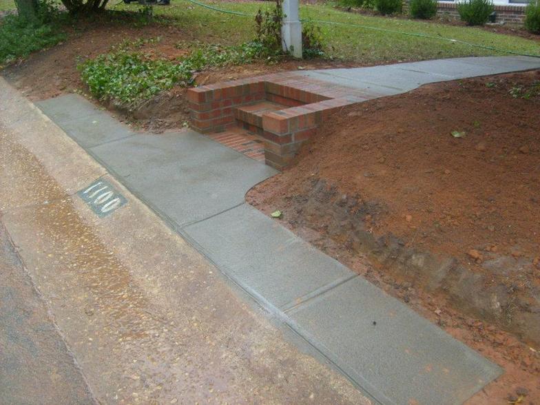 A sidewalk with brick steps leading up to a house.