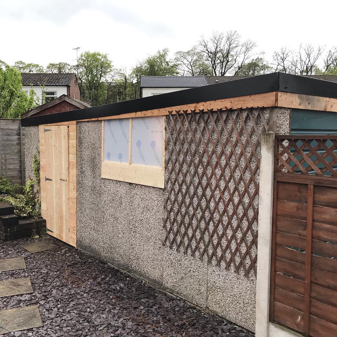 Side of red garage with light gray guttering and sheets