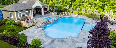 An aerial view of a large swimming pool in a backyard with a house in the background.