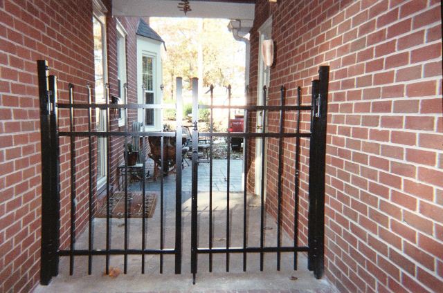 A brick wall with a black gate in front of it