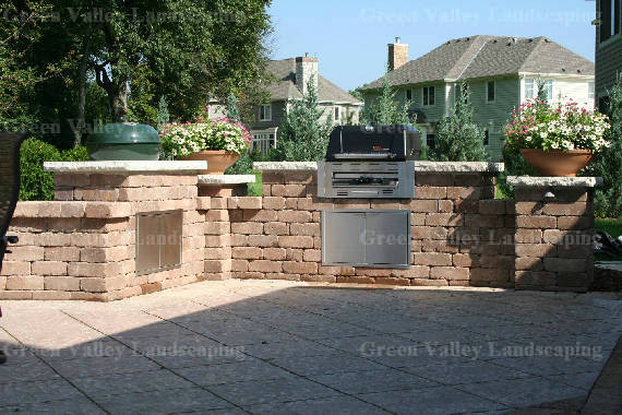 A brick patio with a grill and a fireplace by green valley landscaping