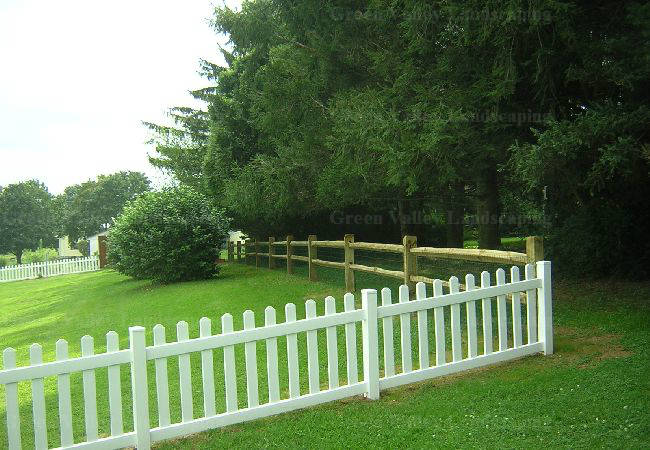 A white picket fence surrounds a lush green field.