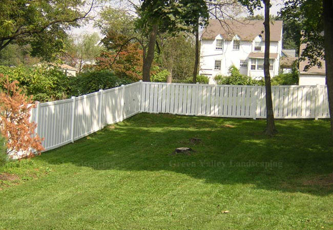 A white picket fence surrounds a lush green yard