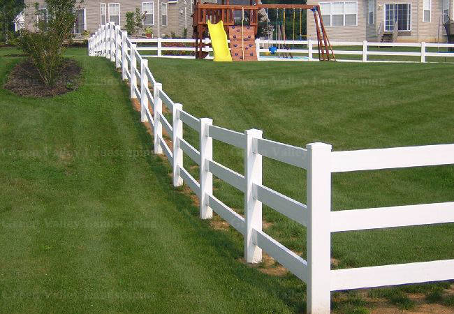 A white fence surrounds a playground in a backyard