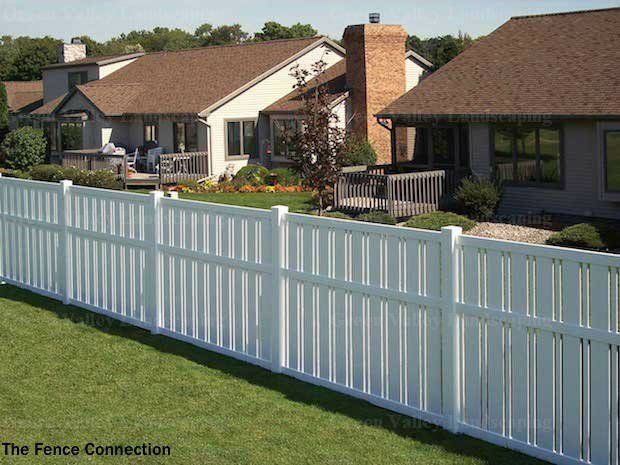 A white fence surrounds a lush green yard in front of a house