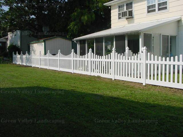 A white picket fence surrounds a house with a screened in porch