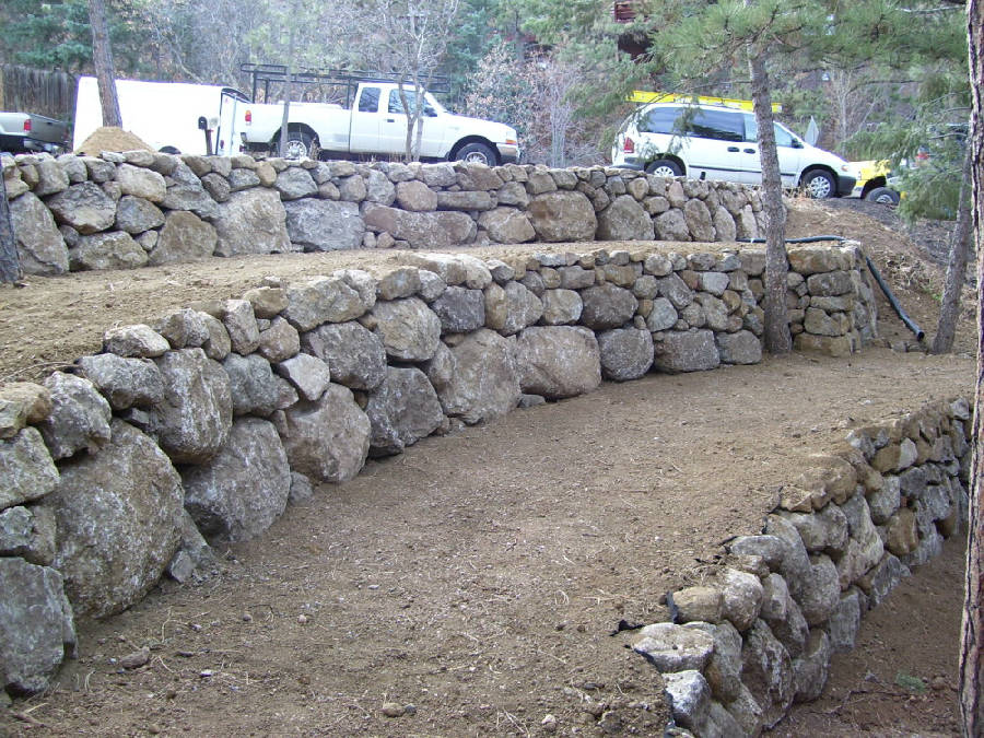 A white truck is parked next to a stone wall