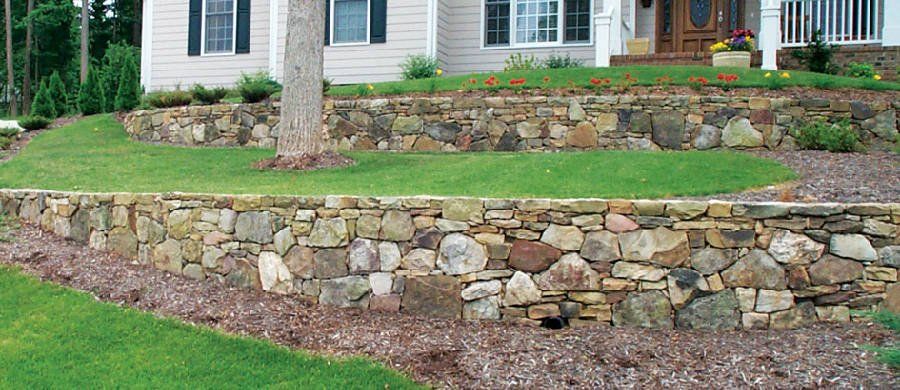 A house with a stone wall in front of it.
