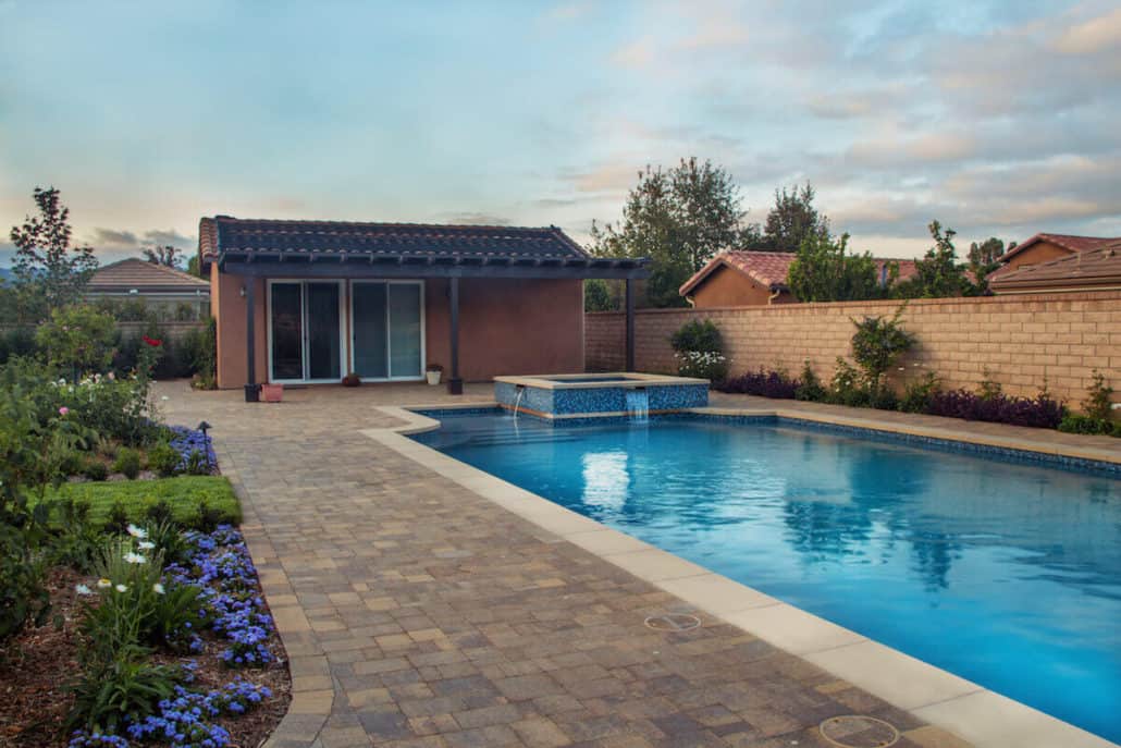 There is a large swimming pool in the backyard of a house.