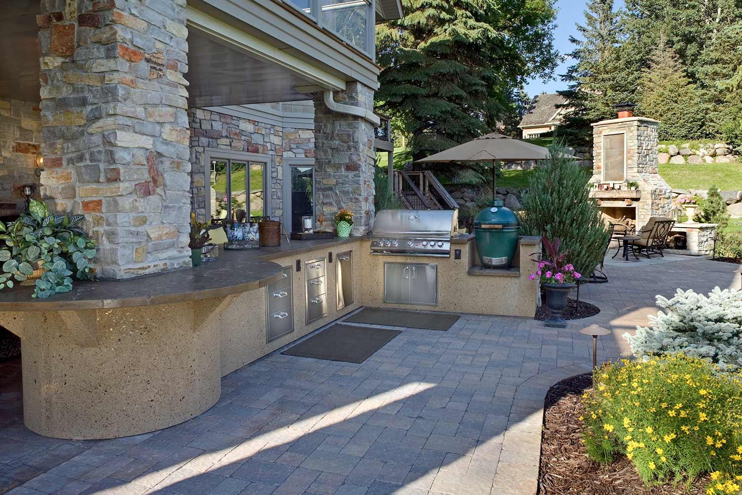 There is a large outdoor kitchen with a grill and umbrellas.