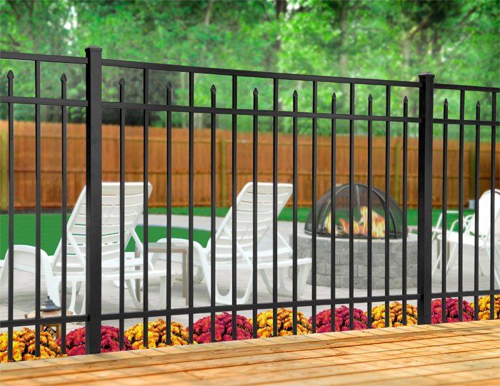 A black metal fence surrounds a patio with chairs and a fire pit.