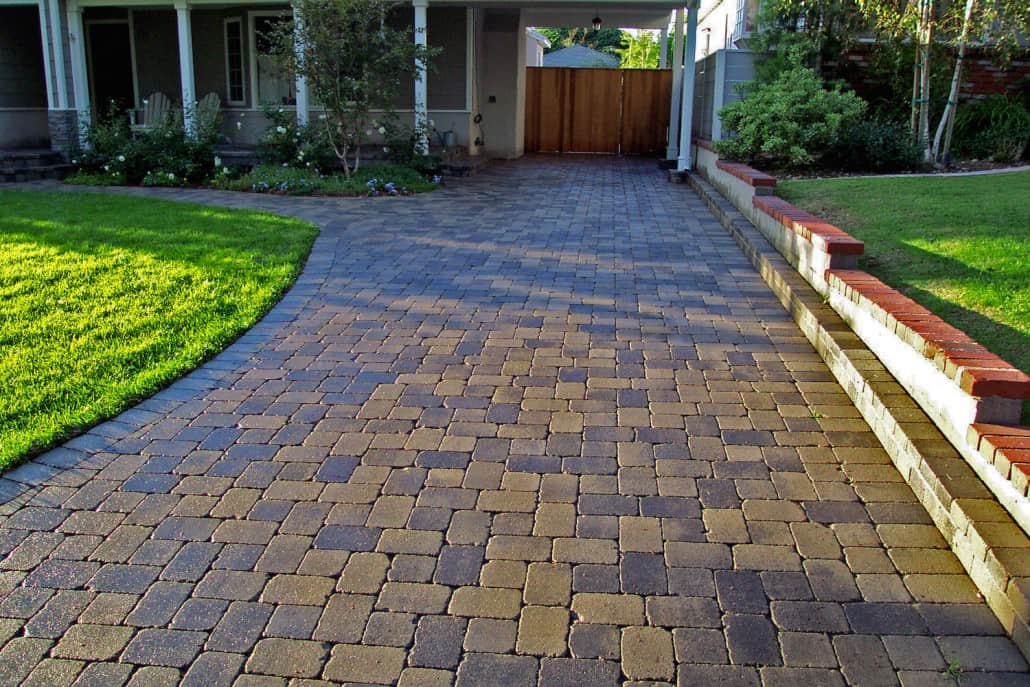 A brick walkway leading to a house with a wooden gate