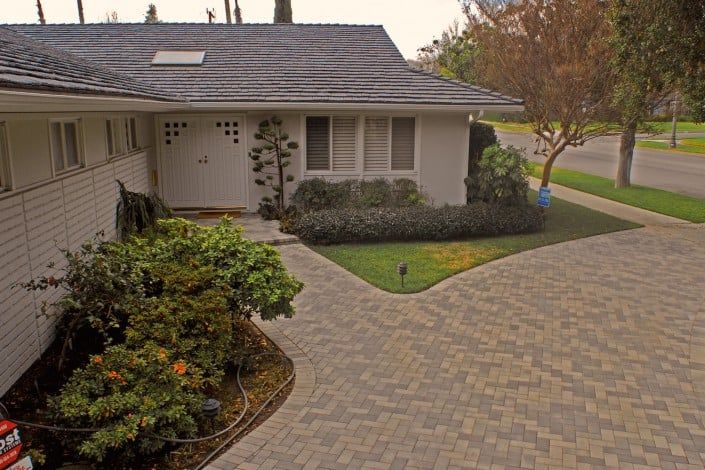 An aerial view of a white house with a brick driveway leading to it.