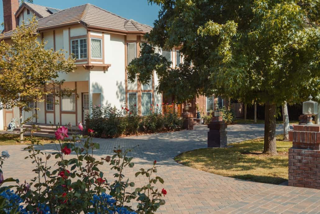 A large white house with a driveway and trees in front of it.