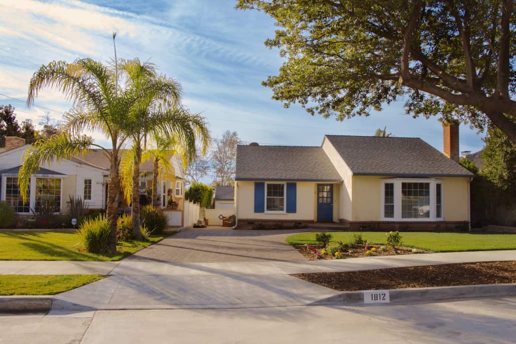 A house with blue shutters and a palm tree in front of it.