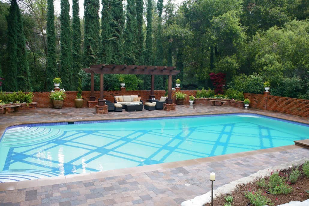 A large swimming pool surrounded by trees and a pergola